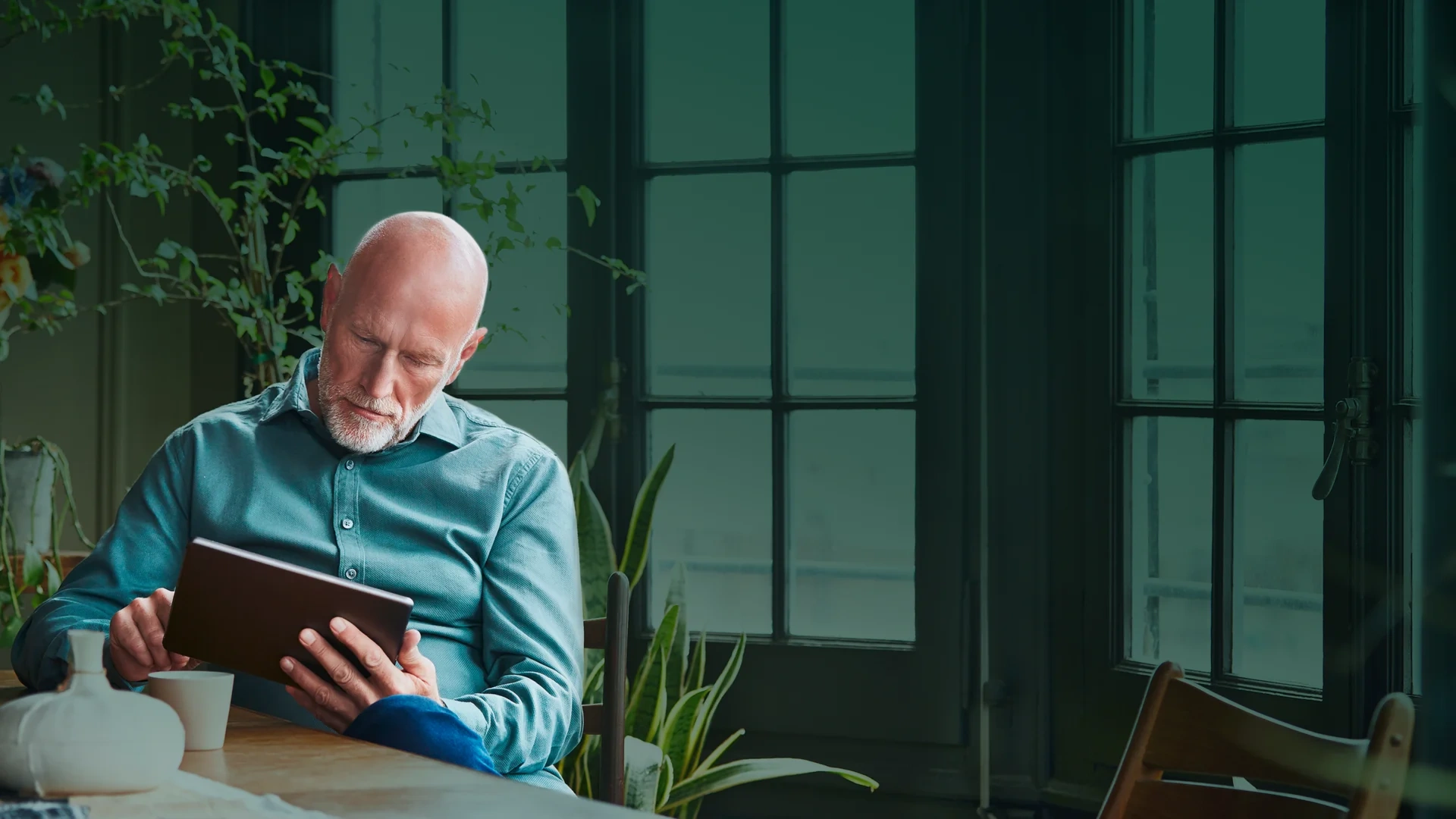 Älterer Mann nutzt ein digitales Tablet am Tisch Altersvorsorge