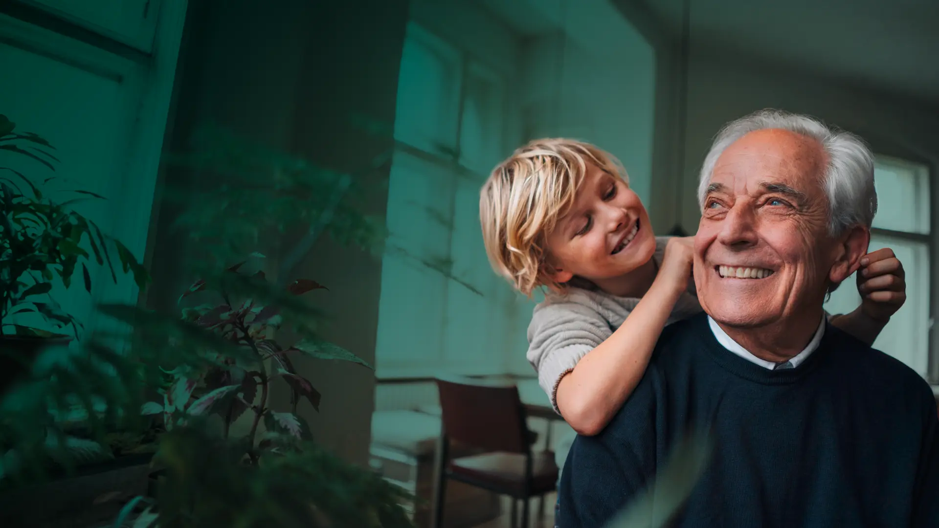 Kind umarmt liebevoll einen älteren Mann von hinten, während beide lächeln