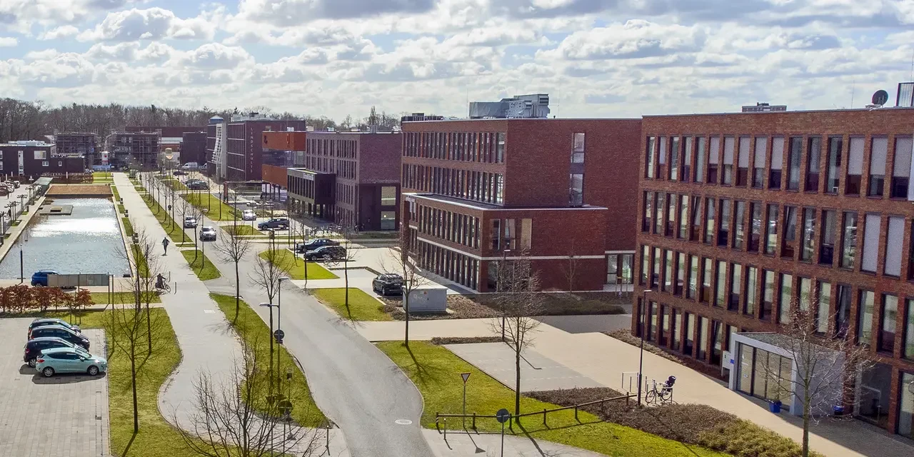 Panoramablick auf das Spiekermann Gebäude in Nordhorn mit moderner Architektur, klaren Linien und großzügiger Glasfassade, eingebettet in die urbane Umgebung unter weitem Himmel