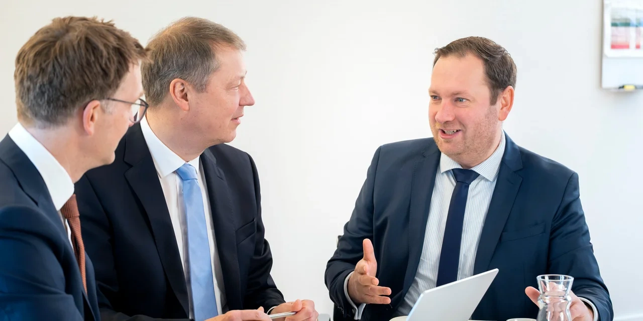 Drei Personen reden miteinander am Tisch
