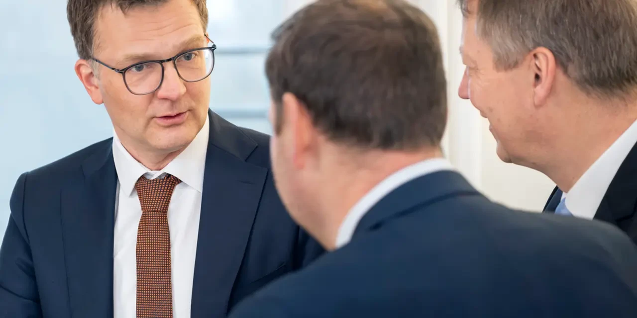 Drei Personen in Anzügen unterhalten sich ernst